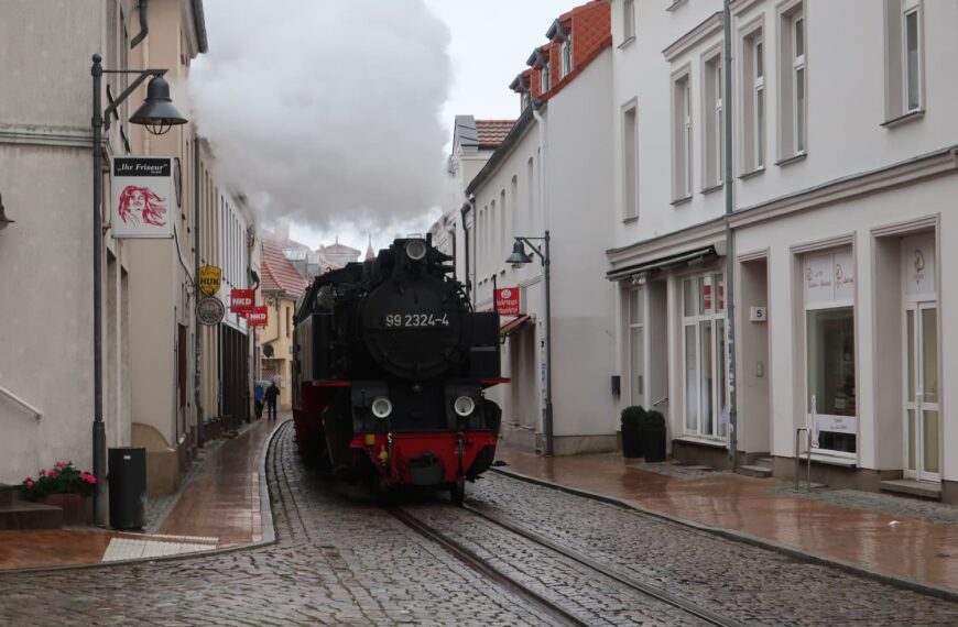 町の通りを走り抜ける蒸気機関車モリー鉄道
